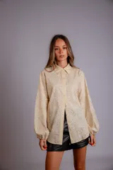 Camisa color crema con bordado de flores blancas, de manga larga abullonada y cuello clásico.