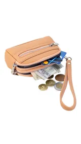 Monedero compacto de símil cuero color beige, con doble compartimento principal con cierre y un bolsillo frontal con cierre. Incluye una correa de mano lateral.