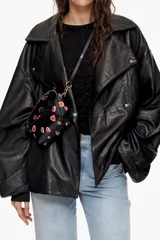 Bolso bandolera negro con estampado de corazones rojos, de tamaño mini, con cierre de cremallera y asa de mano.