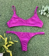 Conjunto de bikini color magenta con acabado metalizado. El corpiño es tipo top con breteles finos y la bombacha es de corte colaless.