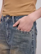 Short de denim azul oscuro con detalles de tachas y pedrería en el bolsillo delantero, de tiro medio y corte holgado.