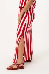 Pollera larga tejida a rayas verticales en color rojo y blanco, con pretina elástica y tajos laterales profundos que aportan movimiento.