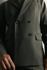Blazer cruzada de traje color verde militar, de corte regular fit, con solapas de muesca, cierre frontal de doble botonadura, bolsillos con solapa en la cadera y bolsillo de vivo en el pecho.