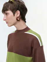 Buzo de punto con diseño de franjas horizontales en azul y blanco sobre fondo negro. Presenta cuello redondo, mangas caídas con puños elastizados y un corte holgado.