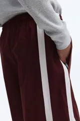 Short deportivo de nylon color bordó, con franjas laterales blancas, cintura elástica con cordón de ajuste blanco y bolsillos laterales.