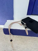 Bandolera negra de nylon con cierre superior y correa larga de cordón trenzado en tonos beige y blanco.