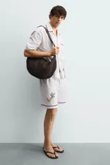 Bolso de hombro de diseño trenzado color marrón, con compartimento principal con cierre de cremallera, bolsillo plano interior y asa de hombro ajustable.