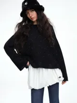 Sweater de punto negro con lentejuelas sutiles, de corte holgado, hombros caídos y mangas largas con terminación acampanada.