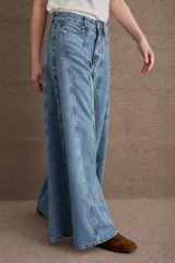 Jean de corte wide leg con tiro alto, confeccionado en denim azul oscuro. Presenta costuras verticales a lo largo de las piernas con pespuntes en color verde a contratono.