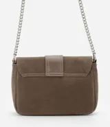 Cartera bandolera pequeña de estructura rígida en gamuza sintética color marrón. Presenta una tapa frontal con detalle de tira central y hebilla decorativa, y una correa larga de cadena metálica.