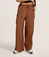 Pantalón wide leg de estilo sastre color marrón, con cintura elástica, lazo ajustable y pliegues frontales. Presenta un corte recto y fluido.