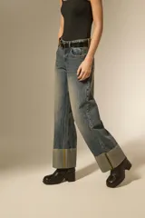 Pantalon jean de corte recto y tiro medio, con un lavado desgastado y un dobladillo ancho en la parte inferior que deja ver el revés de la tela con costuras en contraste.