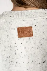 Sweater de punto color gris melange con efecto tweed o salpicado en negro, de calce oversize y cuello redondo.