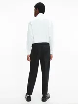 Camisa de corte relajado confeccionada en popelina de algodón con elastano. Presenta cuello clásico, cierre frontal con botones, mangas largas con puños abotonados y un bolsillo frontal con solapa en el pecho.