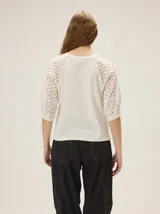 Remera de algodón con escote a la base y mangas raglán de broderie con costuras decorativas en color contrastante.