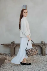 Cartera de hombro con diseño rectangular y solapa frontal, confeccionada en cuero con estampado animal print de leopardo. Cuenta con herrajes metálicos en tono bronce y una correa de hombro ajustable en color negro.