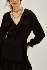 Vestido corto color negro, con escote en V decorado con volados, mangas largas con puños elásticos y falda con volado en el ruedo. Incluye un lazo para ajustar en la cintura.