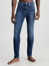 Jeans de hombre con ajuste skinny, talle bajo y pierna estrecha. Denim de algodón elástico con lavado azul oscuro vintage.