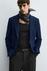 Blazer azul marino de corte recto, confeccionada en tejido con viscosa. Tiene cuello con solapas de muesca, manga larga con puño abotonado, bolsillo de vivo en el pecho y bolsillos de parche en la cadera. El bajo tiene aberturas en la espalda y el cierre es con botonadura frontal.