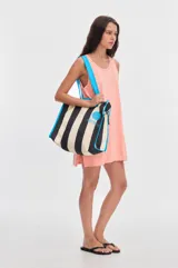 Tote bag de canvas con diseño de rayas verticales en color negro y beige, tiras de hombro y ribetes en color celeste brillante. Cuenta con el logotipo de la marca estampado en el frente con un círculo celeste.