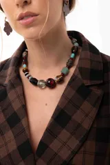 Collar corto compuesto por una variedad de cuentas que incluyen piedras naturales, cristales checos, madera y acrílico en tonos tierra, turquesa y borgoña. Incluye cadena de acero quirúrgico para ajuste de largo.