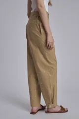 Pantalón color beige con tachas plateadas, tiro alto y corte recto.