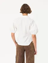 Camisa celeste de popelina, de silueta amplia y diseño liviano. Incluye cuello clásico y cierre frontal con botones.