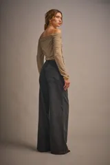 Top negro de microfibra traslúcida esmerilada, ajustado al cuerpo con mangas largas y hombros descubiertos con elástico en el escote.