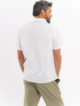 Camisa de manga corta color negro con sutil patrón tipo damero, cuello cubano y cierre frontal con botones.