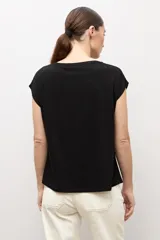 Blusa de manga corta con frente estampado de una gran flor en tonos negro y blanco, y espalda lisa en color negro.