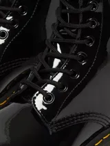 Botas Dr. Martens modelo 1460, de charol negro brillante, con cordones negros, costuras amarillas en la suela y tira trasera con logo AirWair.