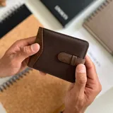 Billetera de formato mediano, combinando símil cuero marrón desgastado y tela canvas azul marino. Posee una presilla de cierre exterior, visor interior, doble compartimento para billetes y tarjeteros.