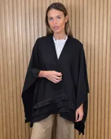 Ruana tejida de algodón en color negro, con diseño amplio y volados en el borde inferior.