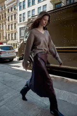 Falda midi de tiro alto color marrón oscuro con efecto piel y arrugado. Incluye un cinturón fino negro con hebilla dorada. Cierre lateral con cremallera oculta.