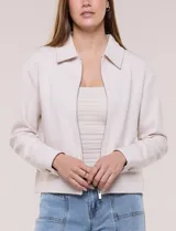 Camperita corta blanca de punto elastizado, con cuello camisero, cierre frontal completo y mangas largas con puños anchos abotonados.