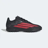 Championes de fútbol Adidas F50 Club para césped artificial, color negro con detalles en rojo y blanco. Presentan un exterior sintético liviano, lengüeta transpirable y suela de caucho con tapones diseñados para un agarre óptimo en canchas artificiales.