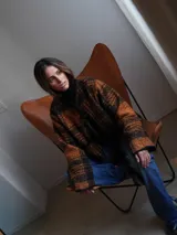 Chaqueta corta con estampado a cuadros en tonos negro, gris y marrón, con ribetes en marrón y cierre frontal con lazos.