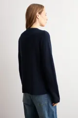 Chaqueta tejida de punto acanalado en color azul marino, con cuello redondo, cierre frontal de botones metálicos y dos bolsillos delanteros aplicados.