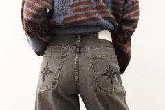 Jean de corte recto y largo, de tiro medio, color gris oscuro con efecto lavado. Presenta un bordado de estrella en los bolsillos traseros.