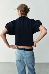 Top de punto color azul marino, con cuello redondo y mangas cortas abullonadas con acabados elásticos fruncidos.