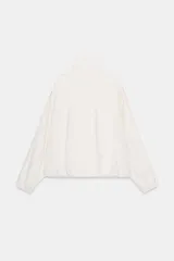 Chaqueta oversize negra confeccionada en hilatura con mezcla de modal, de corte fluido. Cuenta con cuello subido, manga larga con puños elásticos, bolsillos de vivo en el delantero y trabillas en los hombros. El bajo es abullonado con elástico y el cierre frontal es con botones a presión.