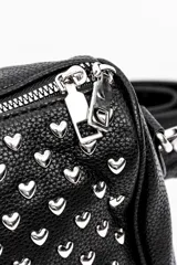 Cartera bandolera negra de formato cilíndrico, completamente cubierta de tachas plateadas en forma de corazón. Cuenta con cierre superior y correa ajustable.