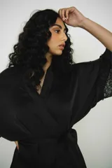 Bata corta de seda negra, con mangas anchas terminadas en encaje. Se ajusta a la cintura con un lazo del mismo material.