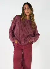 Sweater de punto con diseño de trenzas verticales, cuello redondo y corte holgado. Presenta un acabado texturizado con efecto lavado en color gris oscuro.