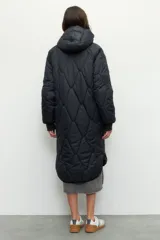 Campera de nylon larga oversized color negro, con capucha, tres bolsillos externos y uno interno. De tela capitoneada, con puños en las mangas y forro polar.