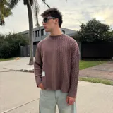 Sweater de punto con diseño bicolor y texturas combinadas, presenta un lado de tejido liso y otro con trenzado vertical. Posee cuello redondo, corte holgado y una etiqueta decorativa en el frente.
