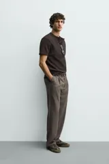 Camiseta de manga corta con cuello panadero y cierre frontal de tres botones. Presenta una textura acanalada y un corte regular fit.