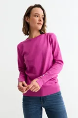 Sweater de punto color fucsia, con cuello redondo, manga larga y puños con abertura lateral decorados con botones brillantes.