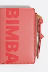 Billetera pequeña de estructura rígida, color negro, con estampado frontal en color dorado con la palabra "BIMBA". Posee cierre superior con tirador de tela amarillo mostaza.