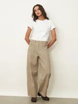 Pantalón tipo jean de corte recto y tiro medio, con estampado de cuadros en tonos beige y marrón. Cuenta con cierre frontal, bolsillos laterales y trabillas para cinturón.